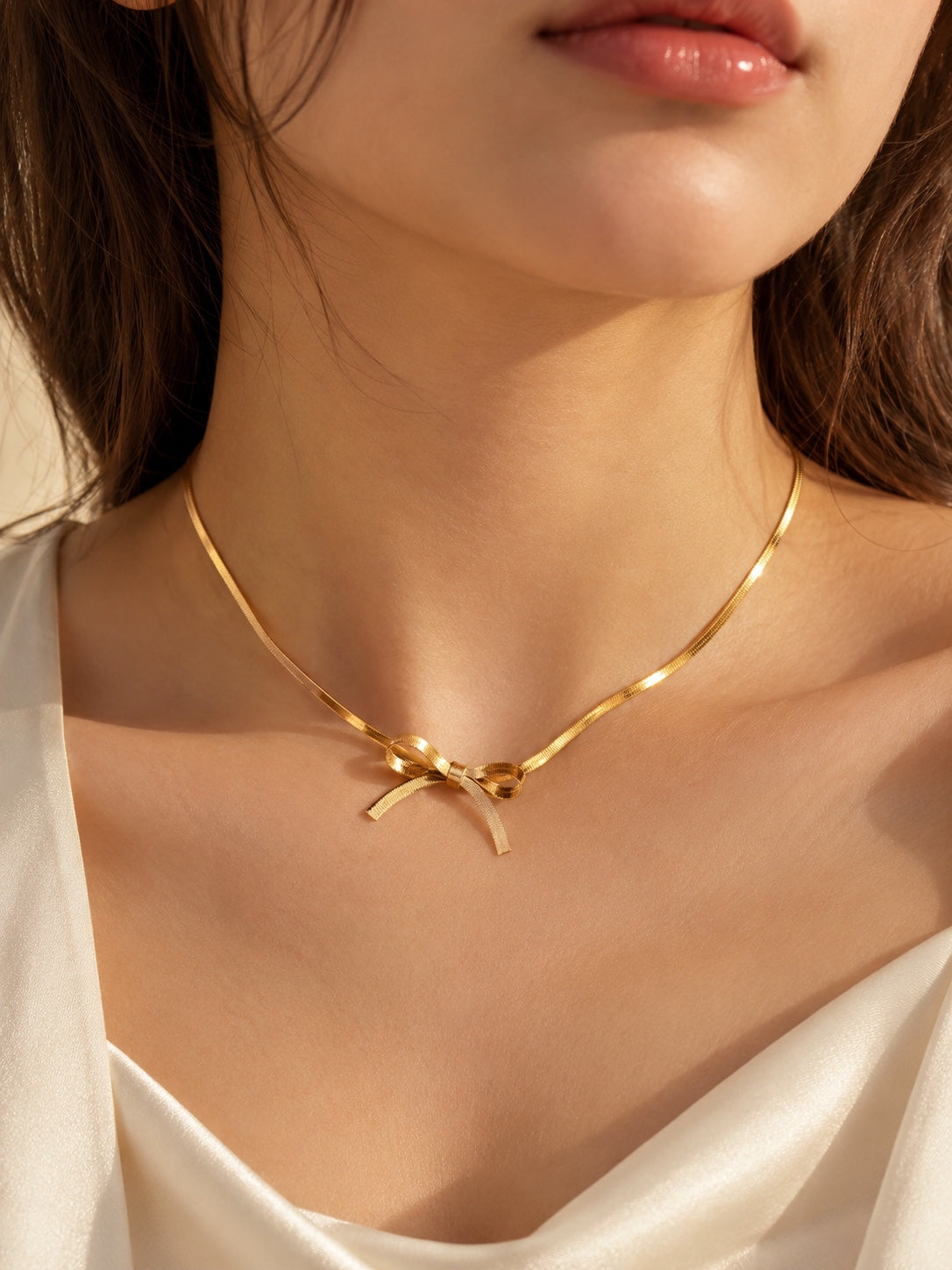 Gold bow necklace worn with an elegant ivory satin outfit