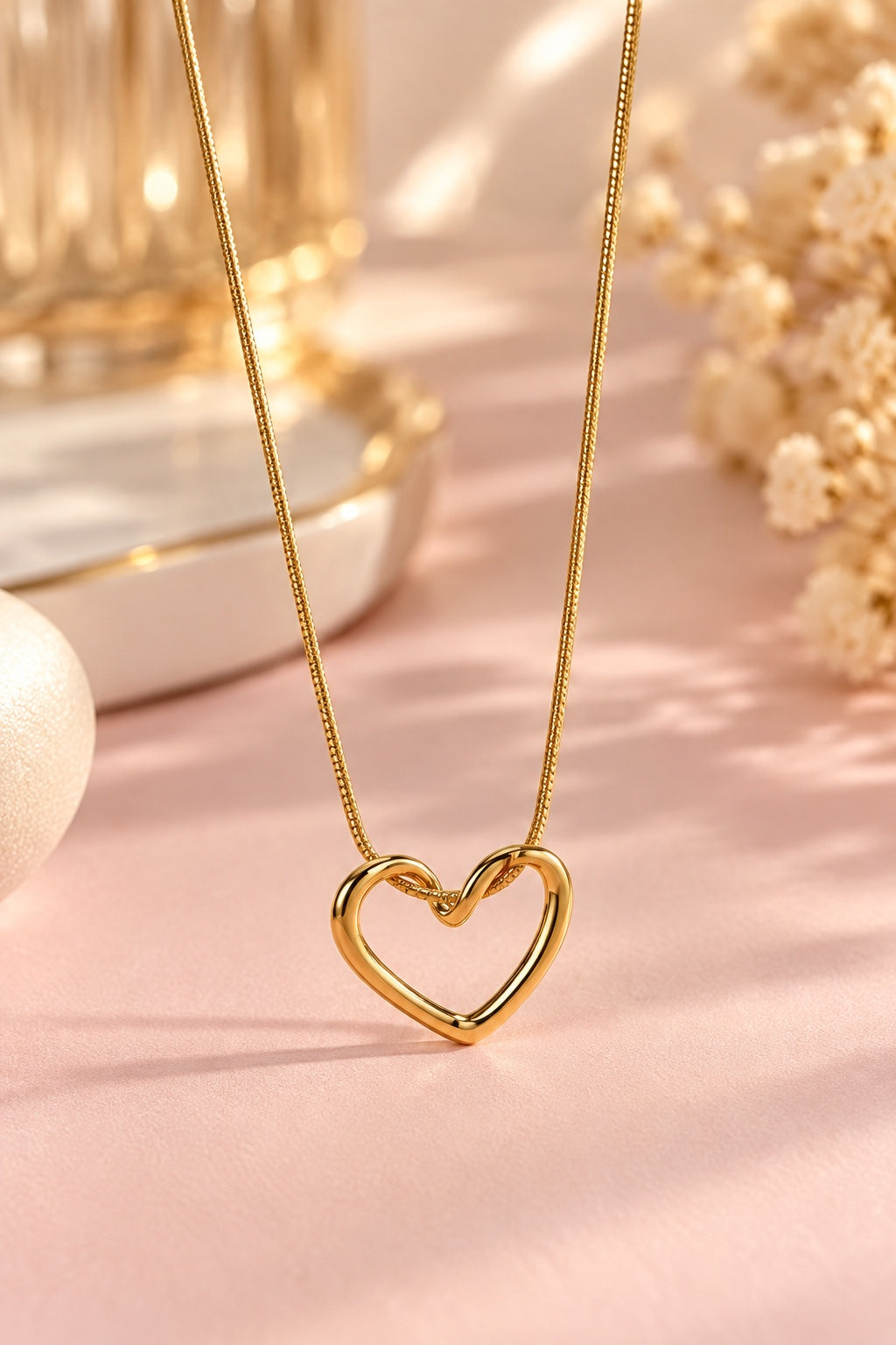 Gold-plated heart necklace on a blush pink surface